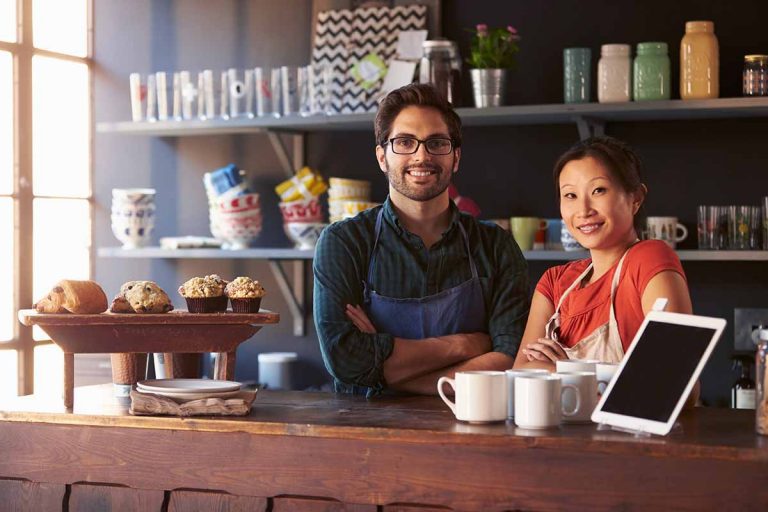 2 people behind a counter running a coffee shop