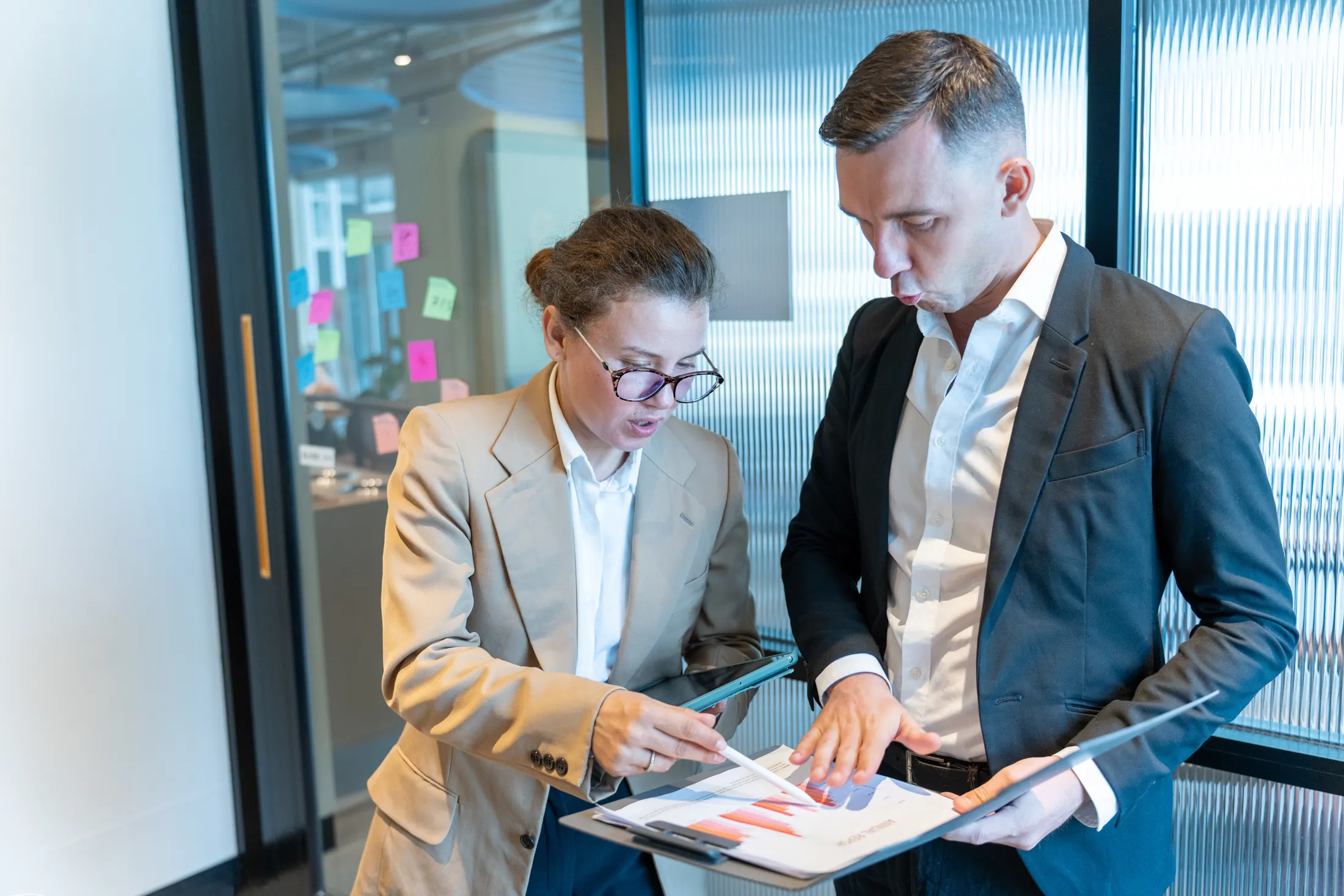 Two business professionals reviewing a document folder and tablet